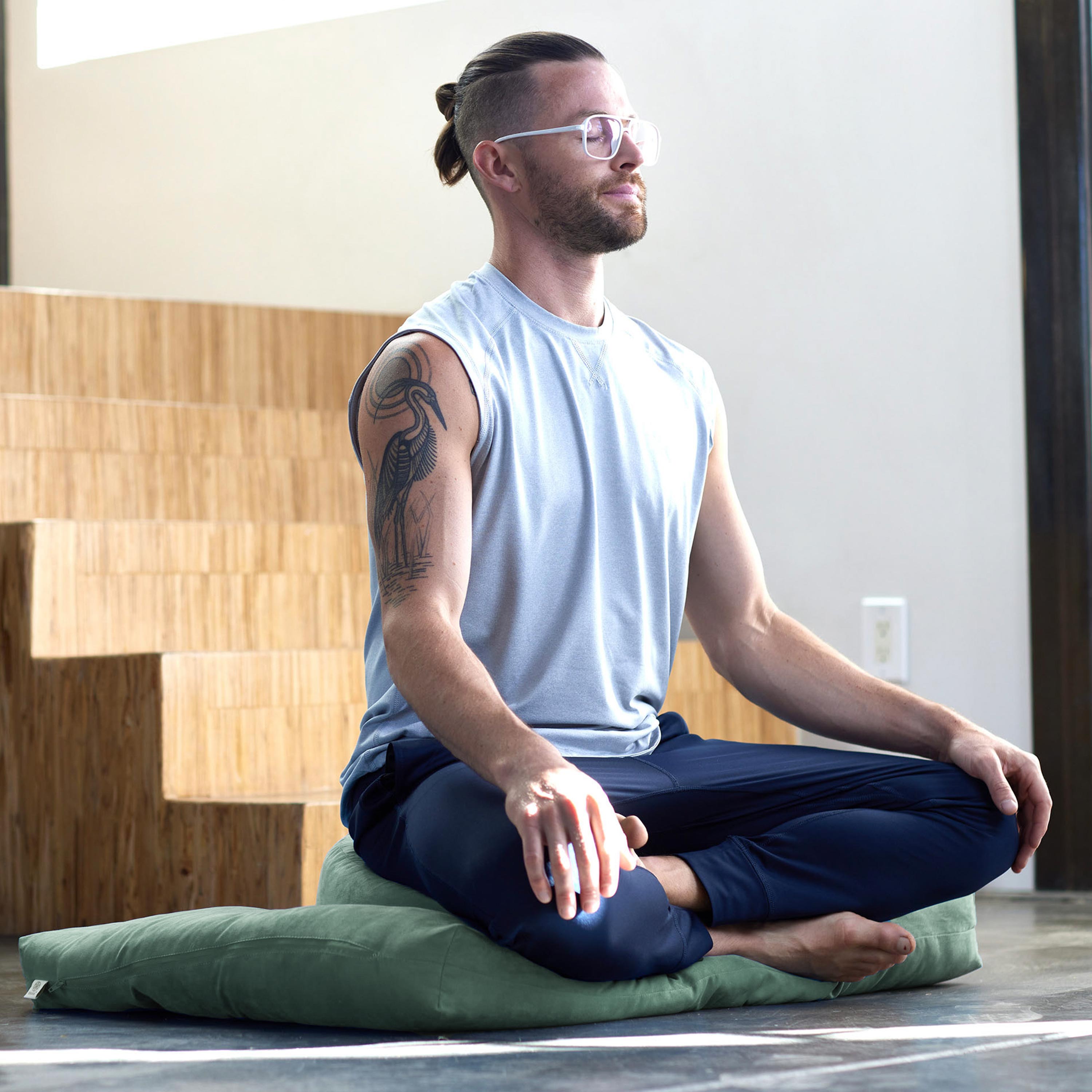 Man sitting on sage meditation cushions